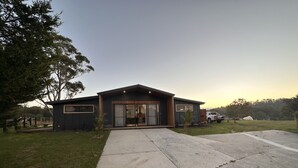A modern two-story house with a large front porch, a garage, and a well-maintained lawn.