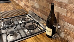 A kitchen with a gas stove, a wine bottle, and wine glasses on the counter.