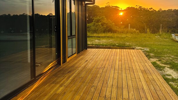 A modern building with large glass windows and a wooden deck.