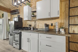 Una cocina moderna con muebles blancos, electrodomésticos de acero inoxidable y techo de madera.