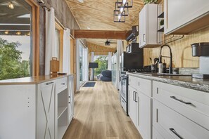 Une cuisine moderne avec des meubles blancs, un plan de travail en bois et une vue sur l’extérieur.