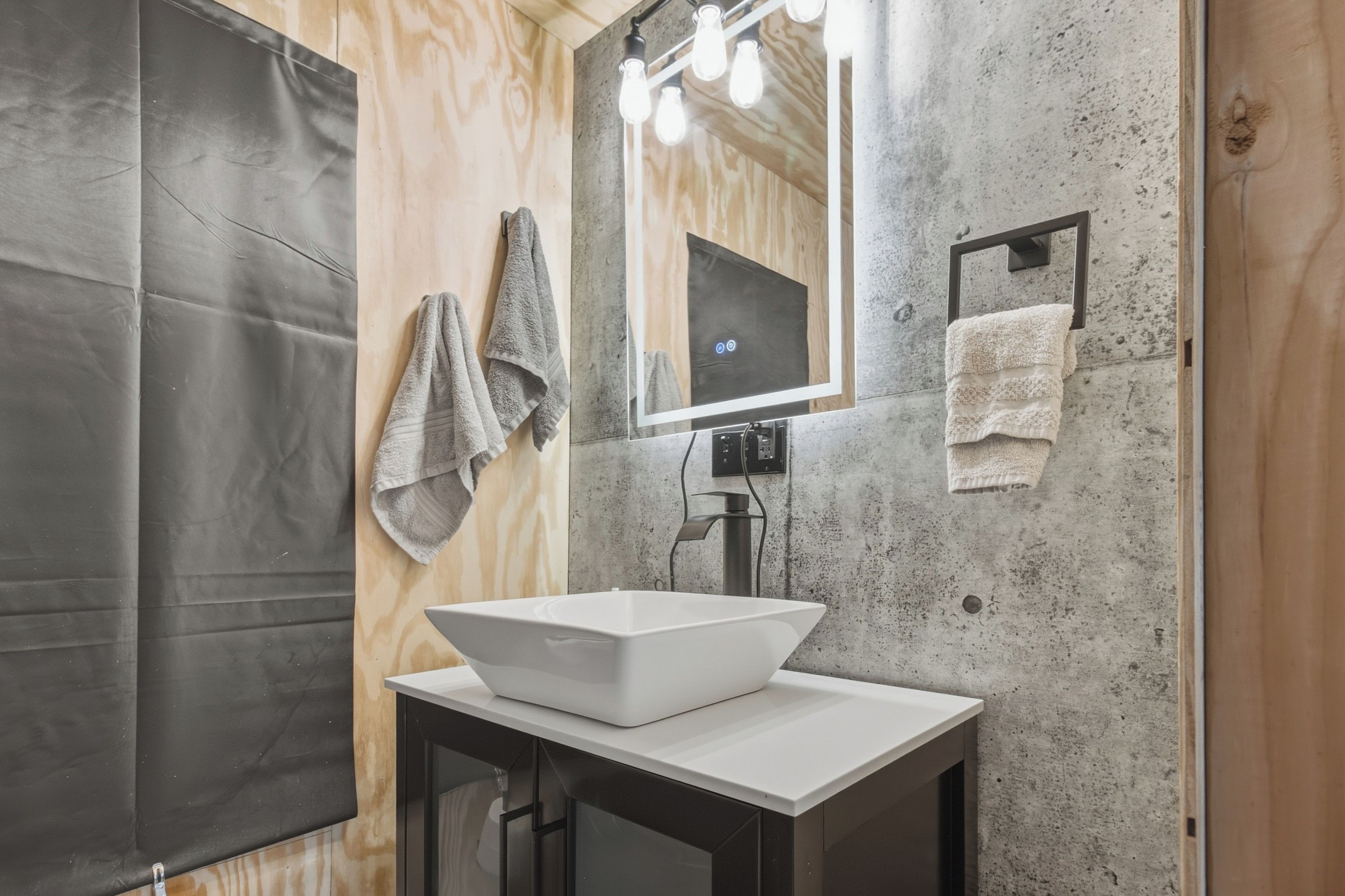 A bathroom with a white vessel sink, a mirror, and towels on a rack.