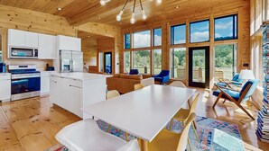 A spacious kitchen with white cabinets, a central island, and a dining area with a large table and chairs.
