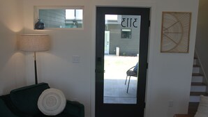 A living room with a dark door, a green sofa, a lamp, and a wall-mounted artwork. - Live in Southside By Trails & Downtown + Parking (Chattanooga)