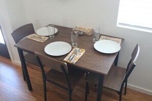Een eettafel met vier stoelen, twee borden, twee glazen en een set zout- en peperstel.