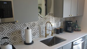 A kitchen with a stainless steel sink, a kettle, a coffee maker, and a microwave. - Live in Southside By Trails & Downtown + Parking (Chattanooga)