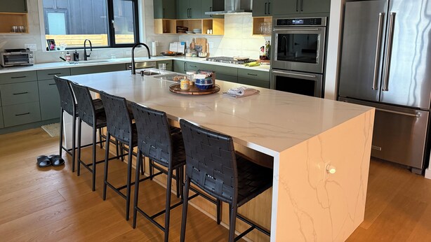 A modern kitchen with a large island, stainless steel appliances, and dark green cabinets. - Parkside Paradise near Montana State University (Bozeman)