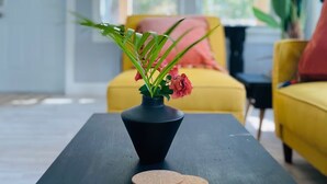 Un soggiorno moderno con un tavolino nero, un vaso con fiori e un divano giallo.