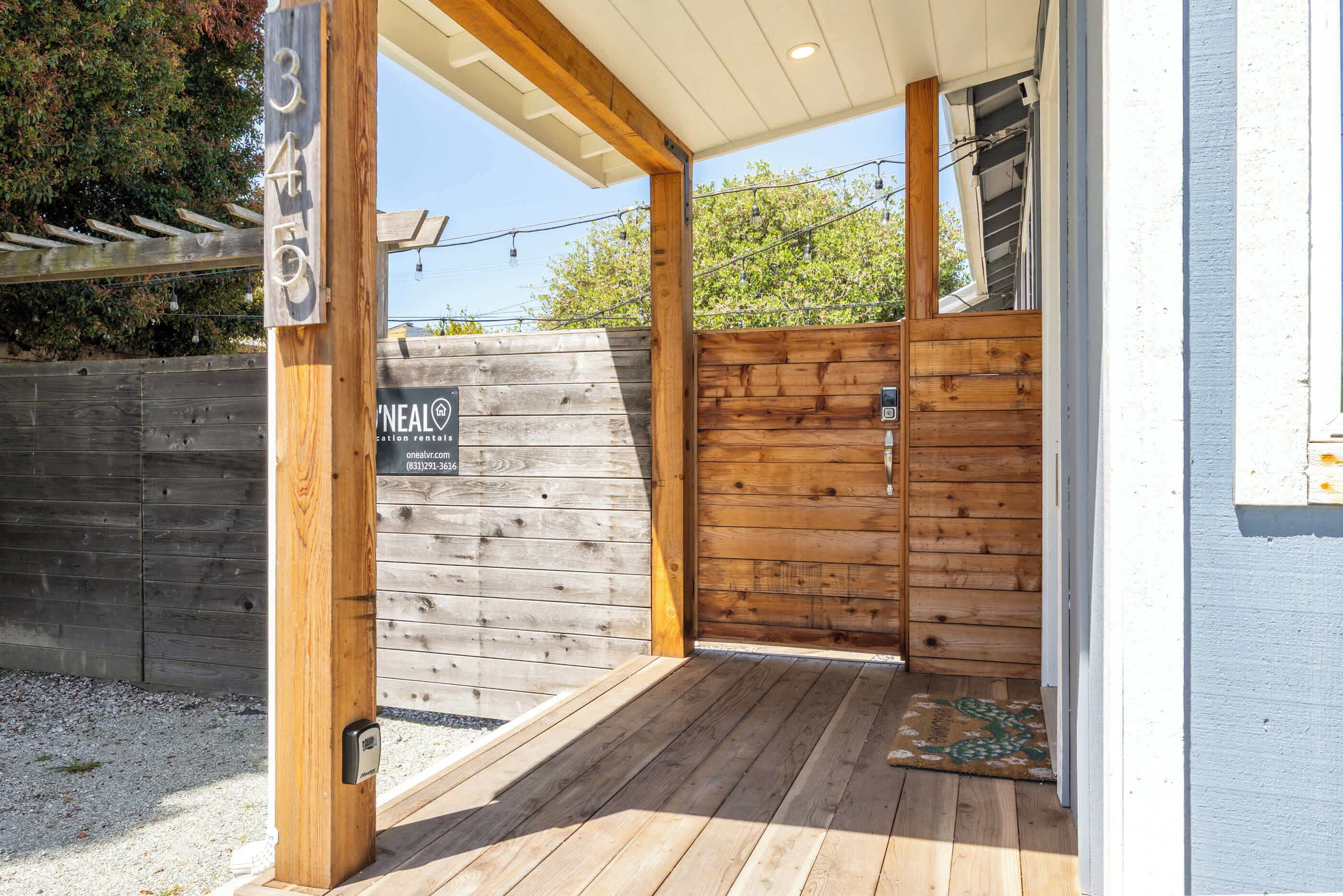 A wooden exterior with a number sign, a wooden door, and a covered porch area.