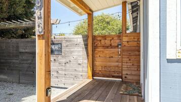 A wooden exterior with a number sign, a wooden door, and a covered porch area.