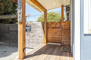 A wooden exterior with a number sign, a wooden door, and a covered porch area.