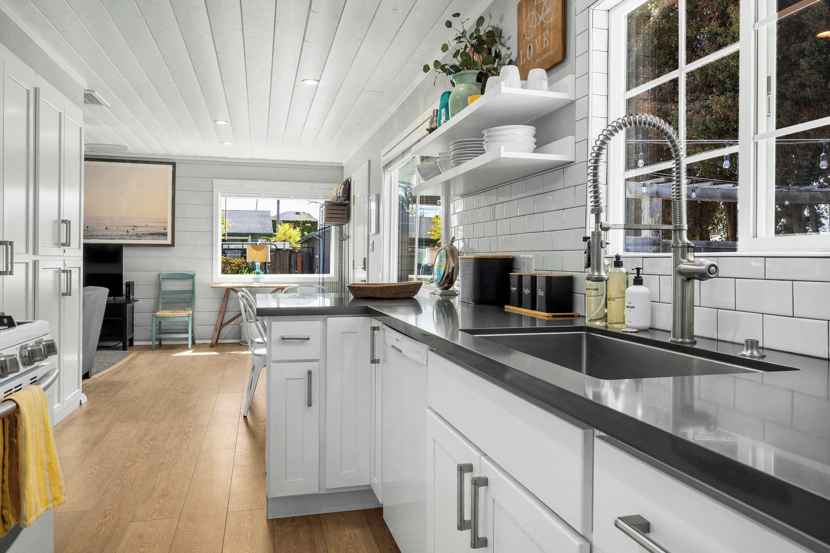 A modern kitchen with white cabinetry, a black countertop, and a window with a view of the outdoors.