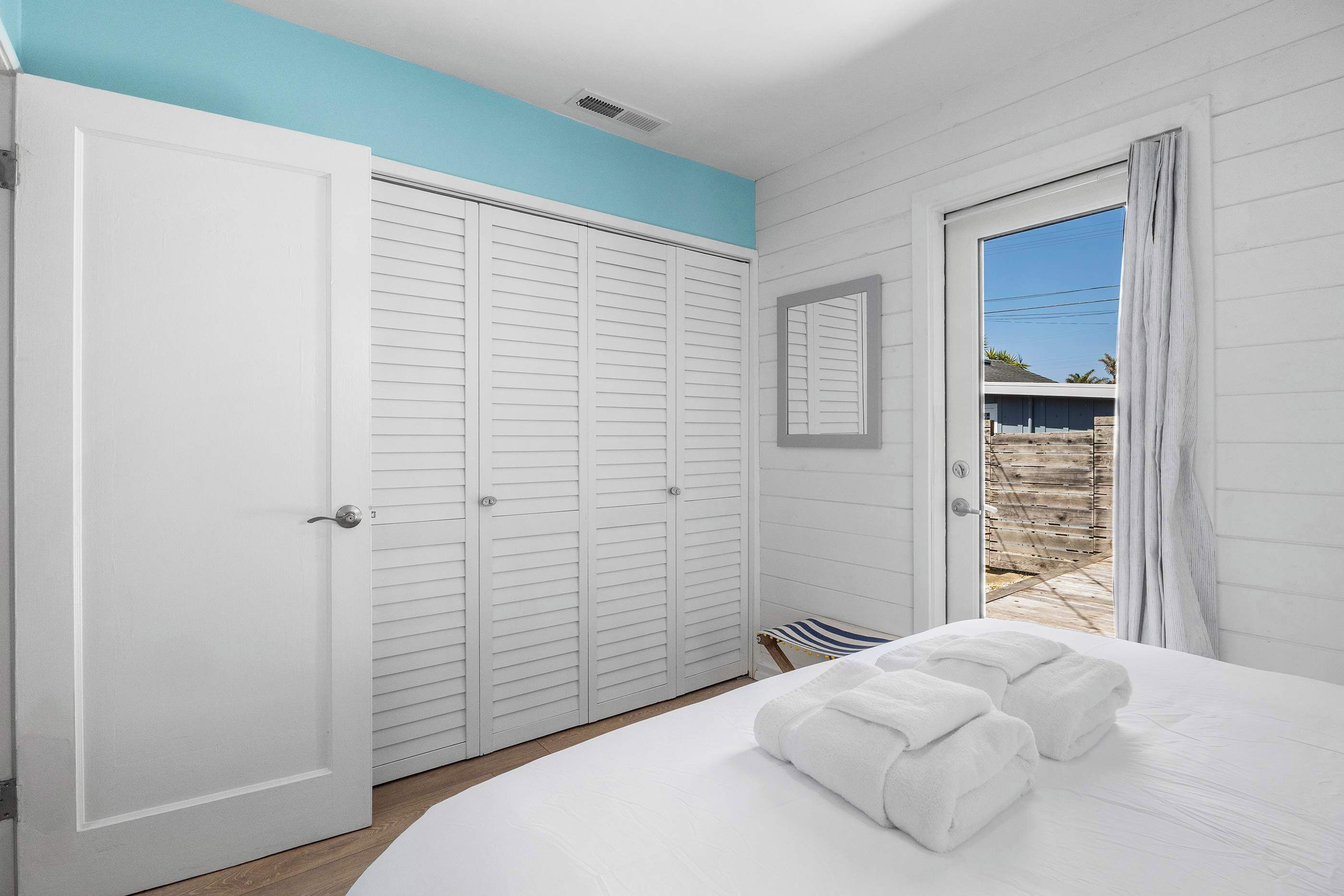 A bedroom with a bed, a wardrobe, and a door leading to an outdoor area.