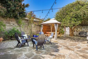 A patio with stone flooring, outdoor furniture, and string lights. - Pet Friendly Pleasure Point Home (Santa Cruz)