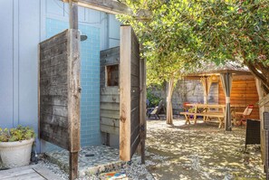 A wooden structure with a window, a stone pathway, and a seating area with chairs and a table. - Pet Friendly Pleasure Point Home (Santa Cruz)