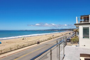 A coastal road with a beach view, a pedestrian walkway, and a building with a balcony overlooking the beach. - 1960's Rio Del Mar Beach House - Stunning Views! (Aptos)