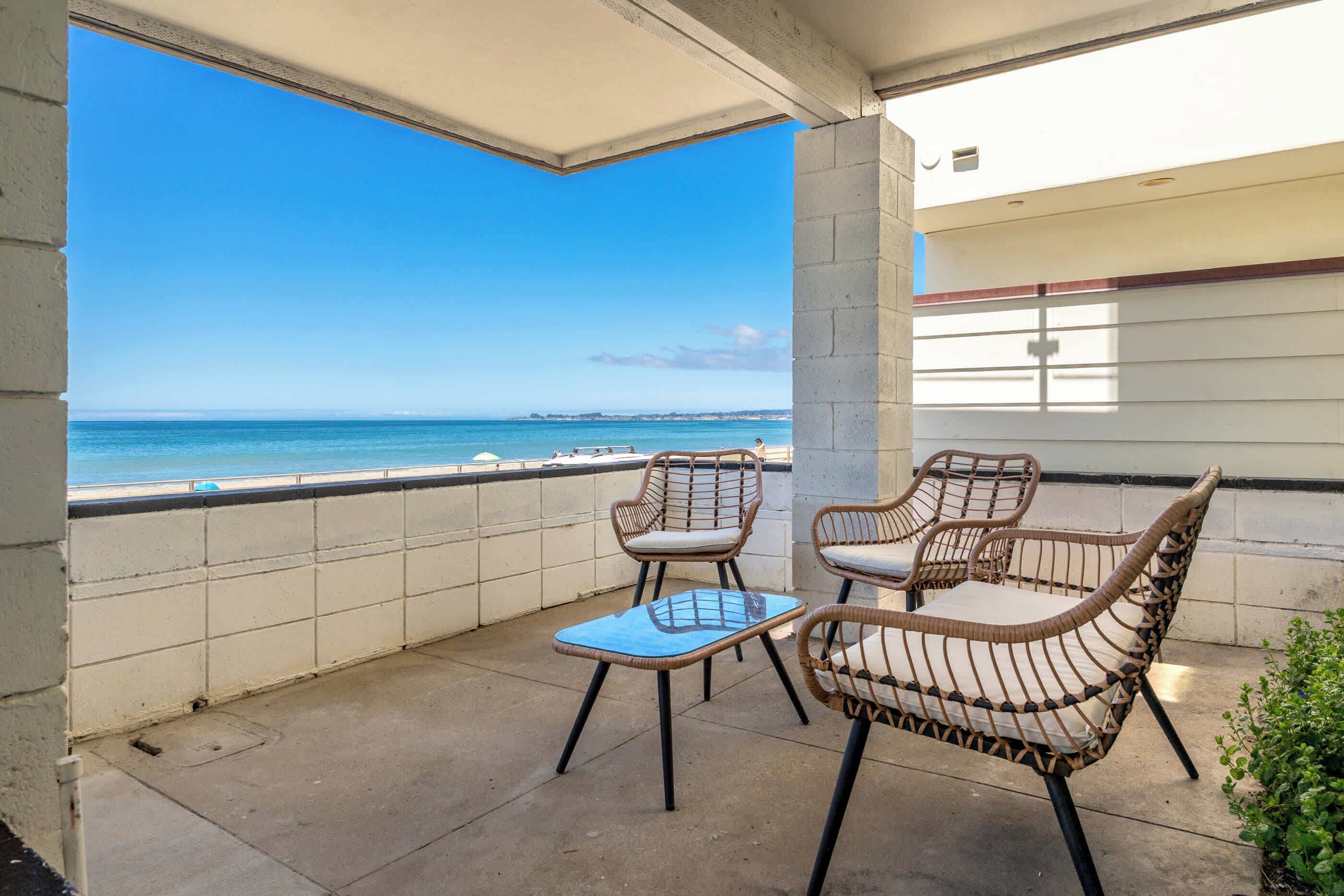 A balcony with wicker furniture and a view of the sea.