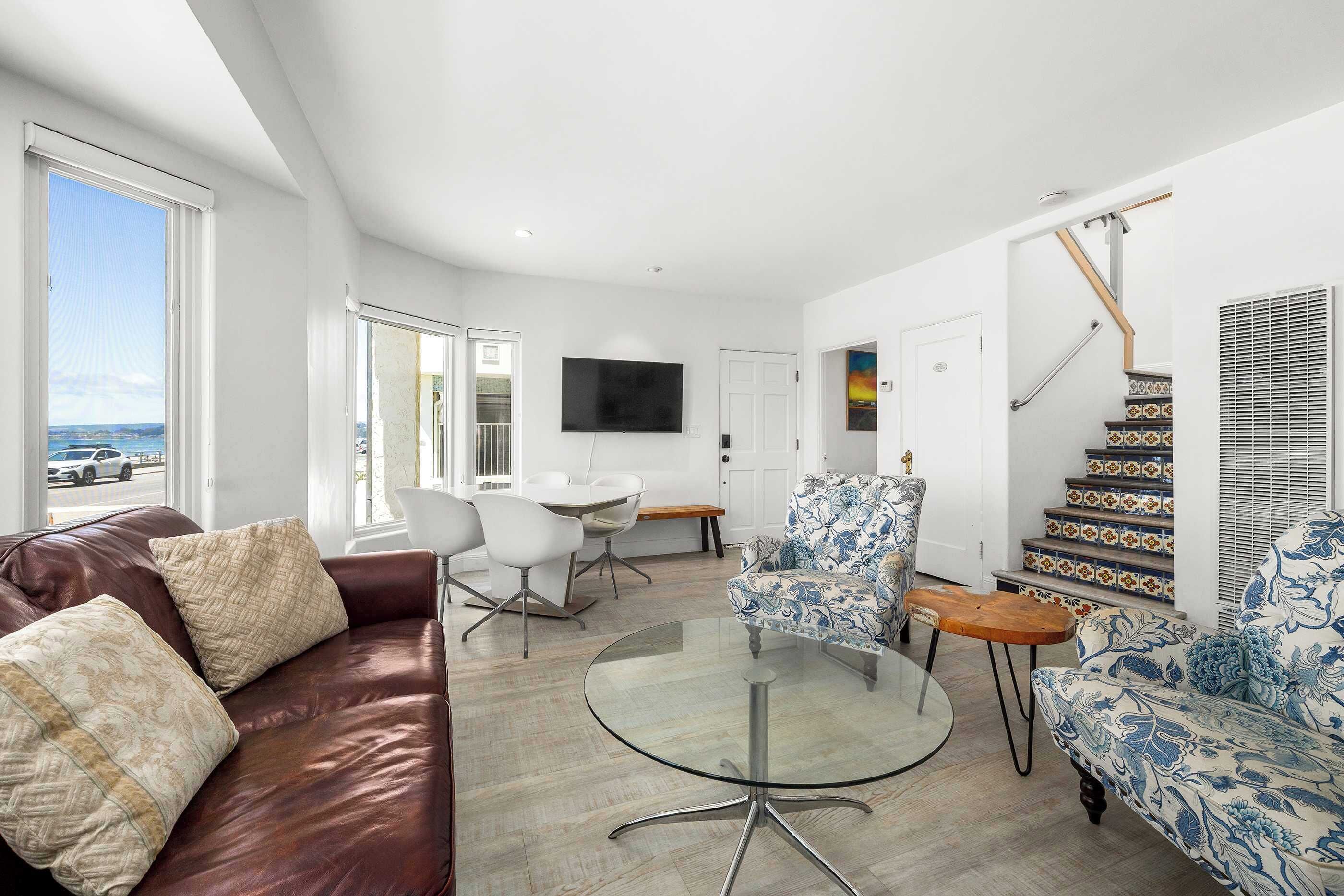 A modern living room with a leather sofa, a glass coffee table, and patterned chairs.