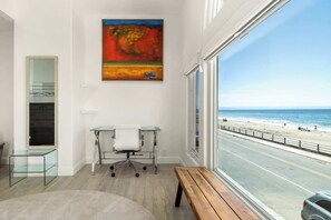 A room with a desk, a bench, and a large window overlooking a beach. - 3 Bedroom Rio Del Mar Home - Steps to Beach! (Aptos)