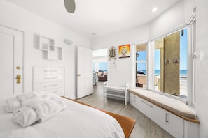 A modern bedroom with a large bed, a bench by the window, and a view of the sea. - 3 Bedroom Rio Del Mar Home - Steps to Beach! (Aptos)