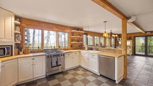 A spacious kitchen with white cabinets, a large island, and a view of the outdoors. - Luxury Mountain Retreat with Hot Tub and Views (Telluride)