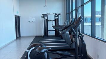 Uma academia com esteiras, elípticos e máquinas de musculação.