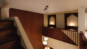 Una escalera de madera con barandilla que lleva a un rellano con una lámpara.