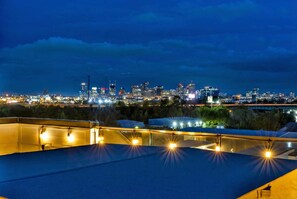A rooftop terrace with a city skyline view at dusk.