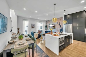 A modern kitchen with a central island, dark cabinetry, and a built-in oven.