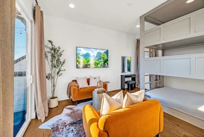 A modern living room with a sofa, a coffee table, a TV, and a bunk bed.