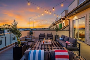 A rooftop terrace with string lights, outdoor furniture, and a view of the sunset. - Fall getaway: 2 Nashville homes, rooftop hot tub & game rooms, sleeps 24 (Nashville)