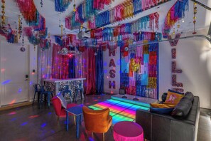 A room with a dance floor, seating area, and a bar.