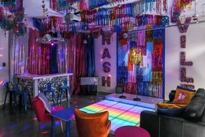 A room with a bar area, a sofa, and a colorful light floor.