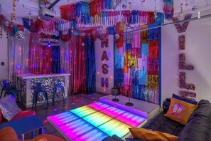 A room with a DJ booth, colorful lighting, and a disco ball.