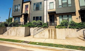 A modern multi-story residential building with a concrete facade, multiple balconies, and a well-maintained lawn.