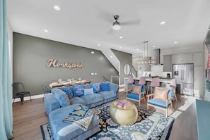 A modern living room with a sectional sofa, a dining area, and a kitchen with stainless steel appliances. - Festival season Nashville house: karaoke & ping pong room, sleeps 12 (Nashville)