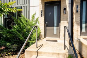 A modern building entrance with a black door, numbered 5165, and a concrete staircase with metal handrails. - Nashville house with rooftop deck, karaoke room & bunk room, sleeps 12 (Nashville)