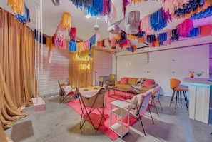 A room with a sofa, chairs, a small table, and a bar area with drinks.