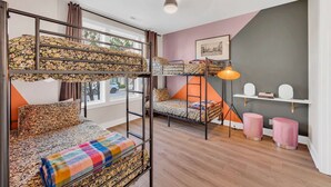 A room with bunk beds, a desk, a chair, a lamp, and a picture on the wall.