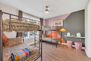A room with bunk beds, a desk, a chair, a lamp, and a picture on the wall.