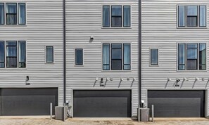 A multi-story building with horizontal siding, multiple windows, and large garage doors. - Nashville house with rooftop deck, karaoke room & bunk room, sleeps 12 (Nashville)