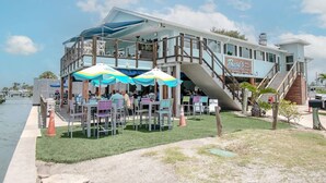 Ein Restaurant am Wasserufer mit Außenbereich, einer überdachten Terrasse und einer Treppe zu einer erhöhten Deckfläche.