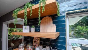 Eine Küchenzeile mit Holzböden, hängenden Pflanzen, einer Kaffeestation und Blick ins Freie.