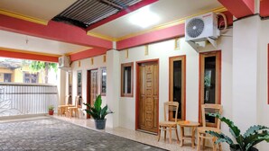 A hotel corridor with tiled flooring, wooden doors, and potted plants. - Hotel O D&a Guesthouse Syariah And Rent Car (Malang)