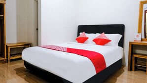 A neatly made bed with a black headboard and white bedding, two red pillows, and a red and white checkered throw. - Hotel O D&a Guesthouse Syariah And Rent Car (Malang)