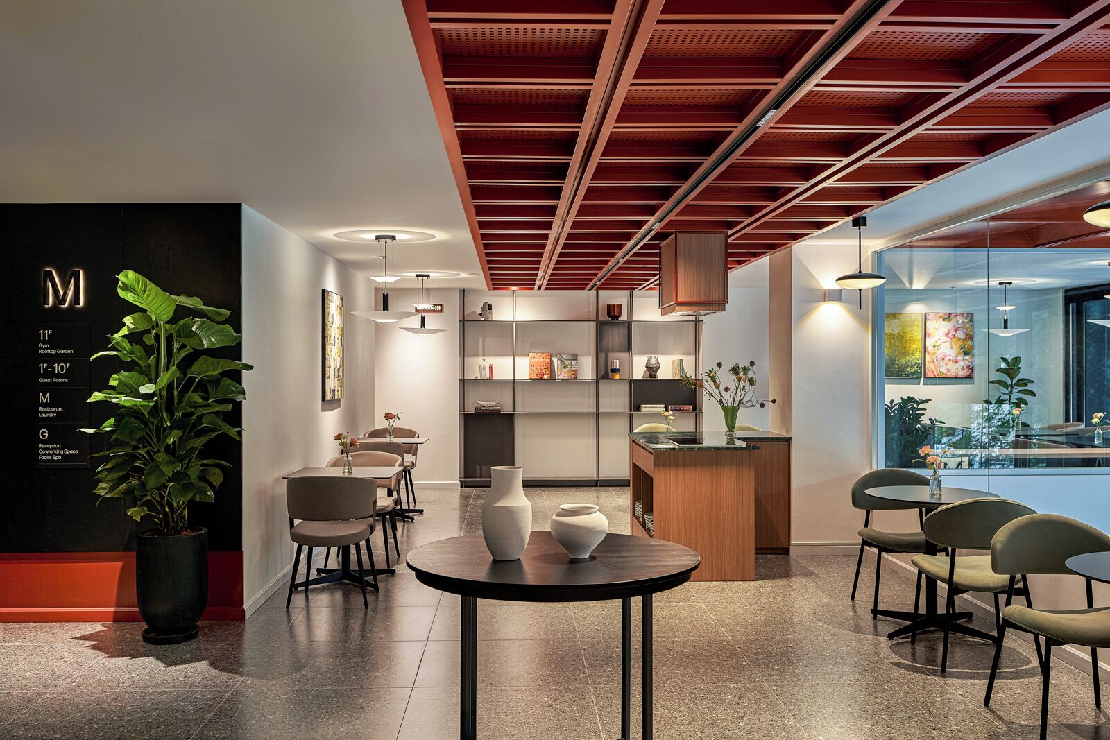 A modern hotel lobby with a reception desk, seating area, and a glass wall offering a view of the outdoors.