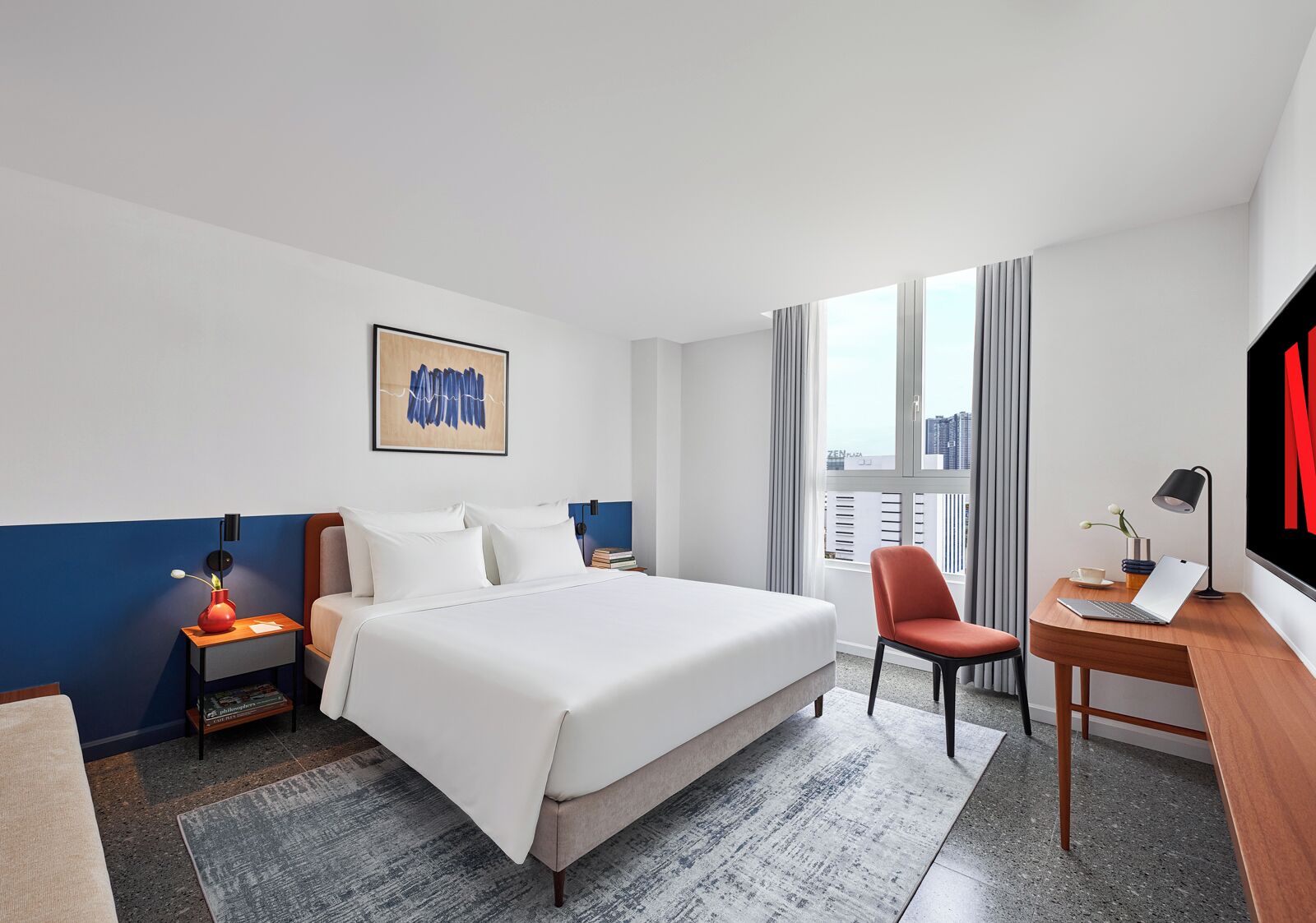 Habitación de hotel con una cama grande, un escritorio con una computadora portátil, una silla, un televisor y una ventana con cortinas.