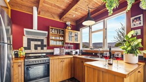 Una cocina con armarios de madera, una estufa y un ventanal con vistas a las colinas.