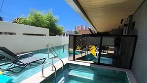 Ein moderner Außenpool mit klarem Wasser, umgeben von Liegestühlen und einer Glaskonstruktion.