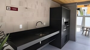 Eine moderne Küche mit schwarzem Arbeitsplatz, Edelstahlgeräten und einer Holzbeschichtung an der Decke.